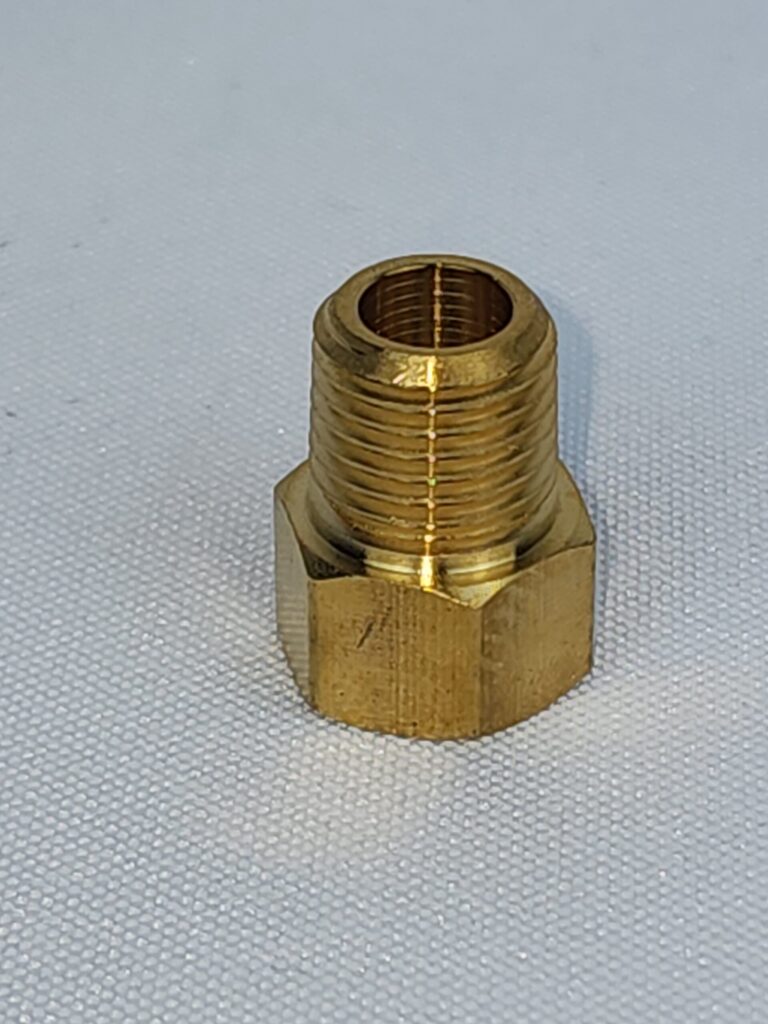 A brass pipe fitting sitting on top of a white surface.